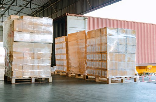 Stack of cardboard boxes on pallet at distribution warehouse for load into container